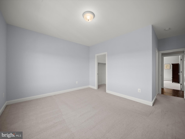 unfurnished bedroom featuring carpet floors, baseboards, a closet, and a walk in closet
