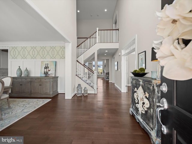 entrance foyer featuring dark wood-type flooring, baseboards, stairs, and a high ceiling