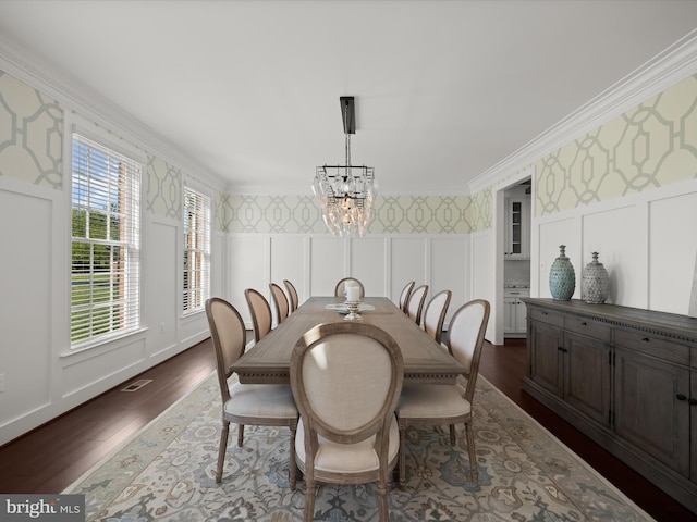 dining area featuring dark wood finished floors, a decorative wall, a notable chandelier, and wallpapered walls