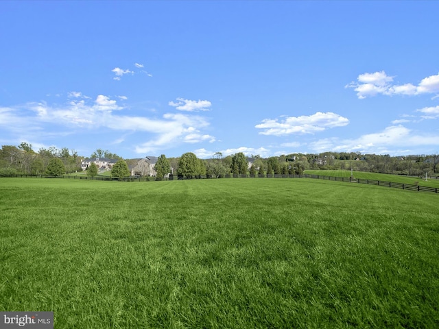 view of yard with fence and a rural view