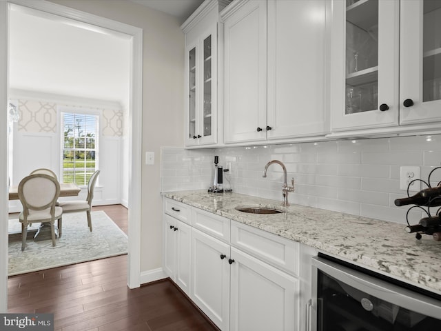 bar featuring wet bar, dark wood finished floors, a sink, baseboards, and beverage cooler