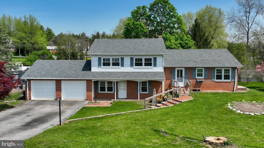 1571 N Dr, York, PA 17408 - tri-level home with a front lawn, a chimney, driveway, brick siding, and an attached garage