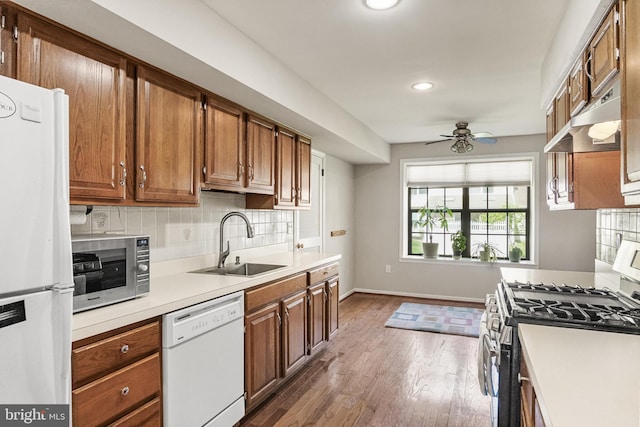kitchen with a sink, stainless steel appliances, under cabinet range hood, dark wood-style flooring, and a ceiling fan