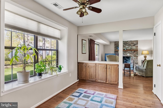 interior space with visible vents, ceiling fan, baseboards, light wood-type flooring, and a fireplace