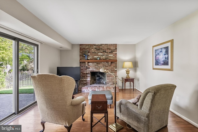 living area with baseboards, wood finished floors, and a fireplace