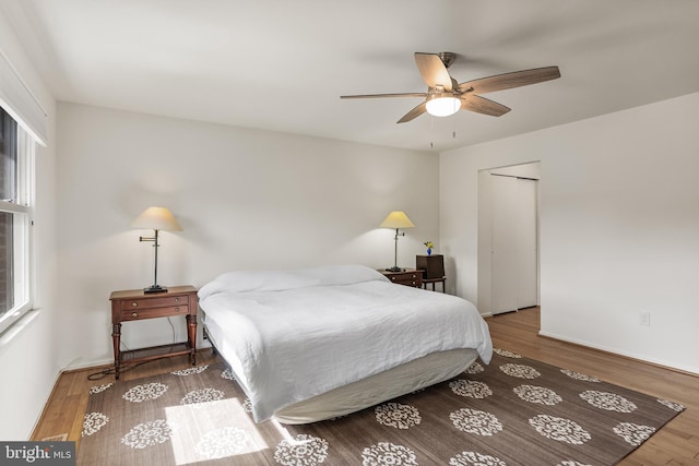 bedroom featuring wood finished floors, a ceiling fan, and multiple windows
