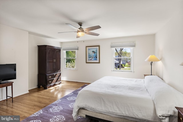 bedroom featuring ceiling fan, light wood finished floors, and baseboards