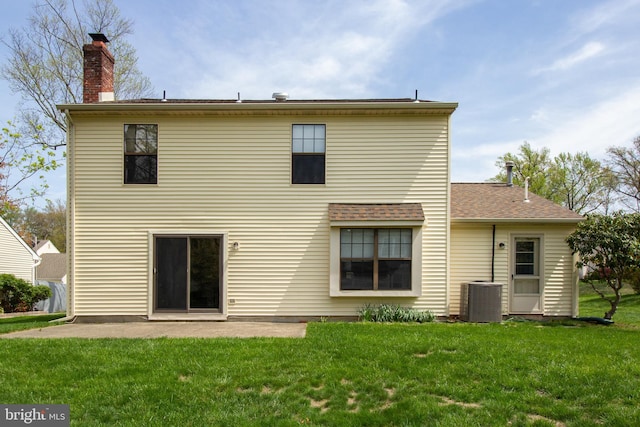 back of house with a chimney, central AC unit, a yard, and a patio