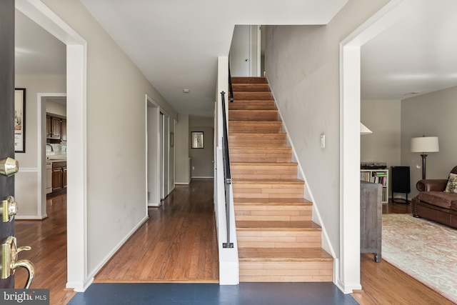 stairs featuring wood finished floors and baseboards