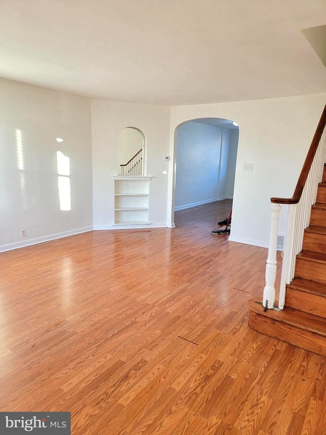 7107 Oakland St, Philadelphia, PA 19149 - unfurnished living room with arched walkways, stairway, light wood-style flooring, and baseboards