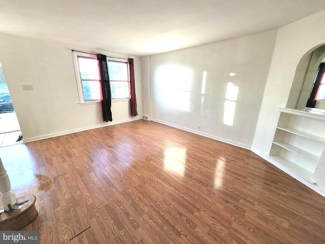 7107 Oakland St, Philadelphia, PA 19149 - unfurnished living room featuring wood finished floors, built in shelves, arched walkways, and baseboards