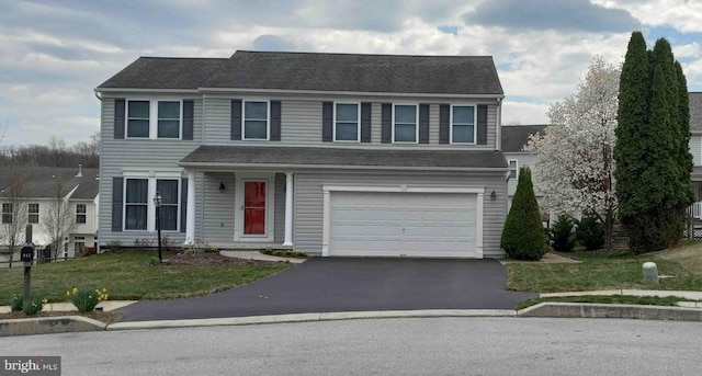 traditional home with a front yard, a garage, and aphalt driveway