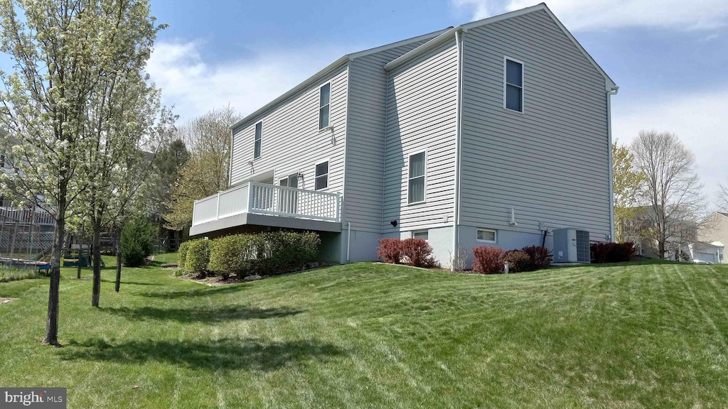 view of side of property with a deck, central air condition unit, and a yard