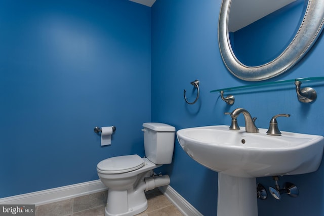 half bathroom with baseboards, tile patterned flooring, and toilet