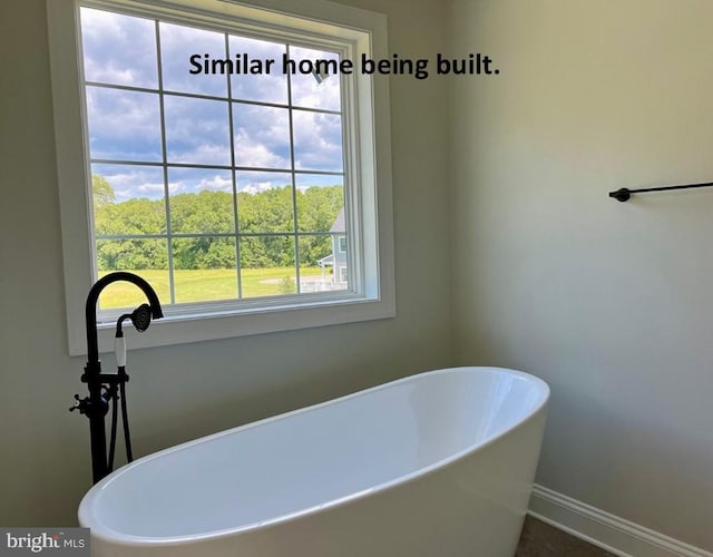 full bath featuring a freestanding bath and baseboards
