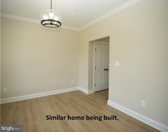 empty room featuring an inviting chandelier, wood finished floors, ornamental molding, and baseboards