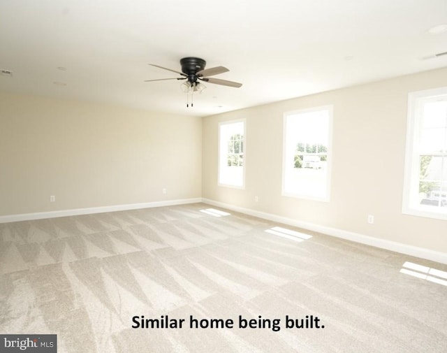 empty room with light colored carpet, ceiling fan, plenty of natural light, and baseboards