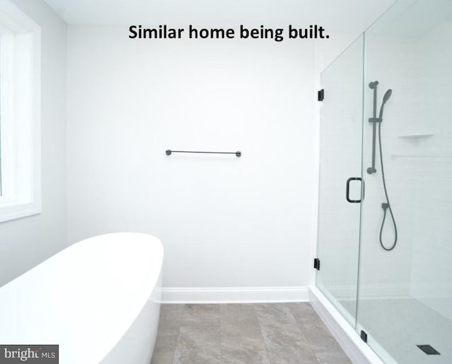 bathroom featuring a soaking tub, baseboards, and a stall shower