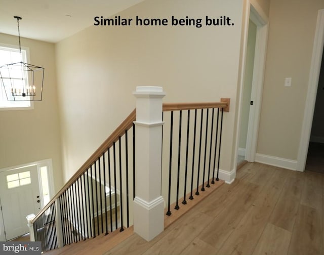 stairway featuring wood finished floors, a chandelier, and baseboards