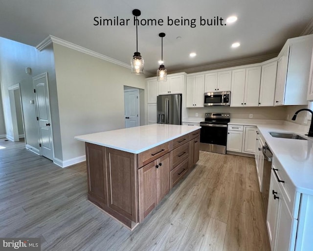 kitchen with a sink, light wood-style floors, crown molding, baseboards, and appliances with stainless steel finishes