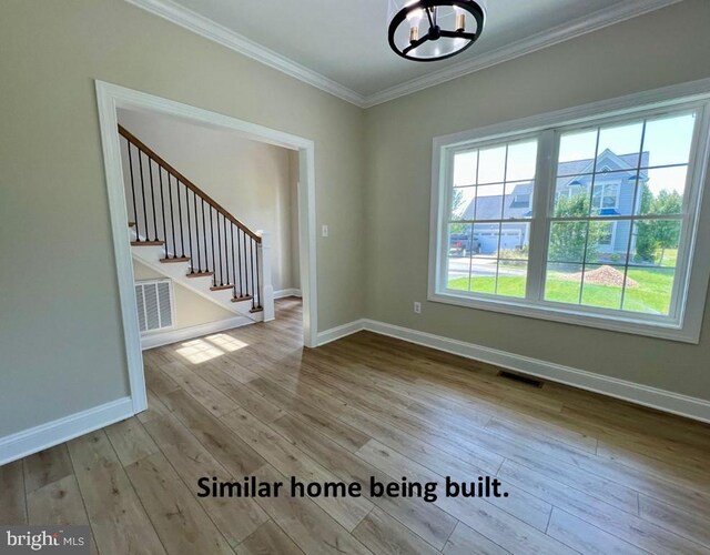 interior space featuring baseboards, wood finished floors, a notable chandelier, and crown molding