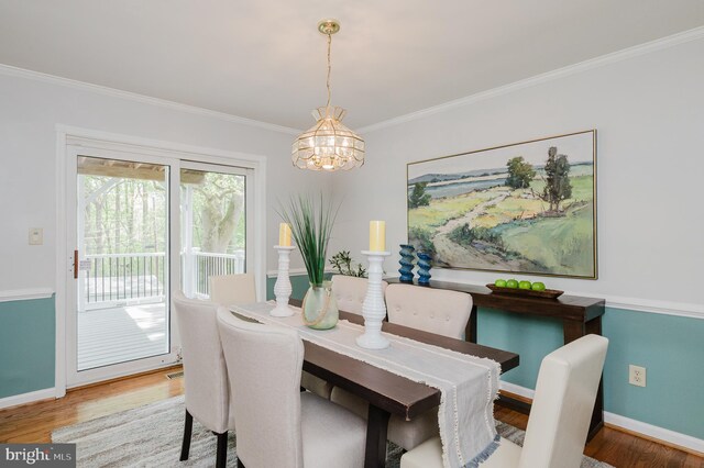 dining room with baseboards, ornamental molding, wood finished floors, and a notable chandelier