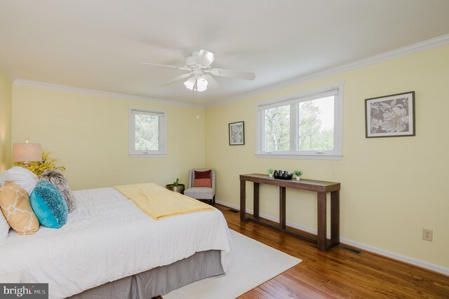 bedroom with visible vents, ornamental molding, baseboards, and wood finished floors