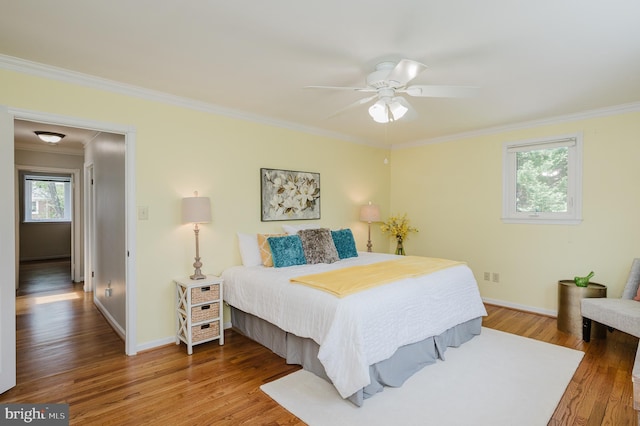 bedroom featuring crown molding, baseboards, ceiling fan, and wood finished floors
