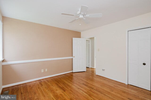 unfurnished bedroom featuring baseboards, a ceiling fan, a closet, and light wood-style flooring