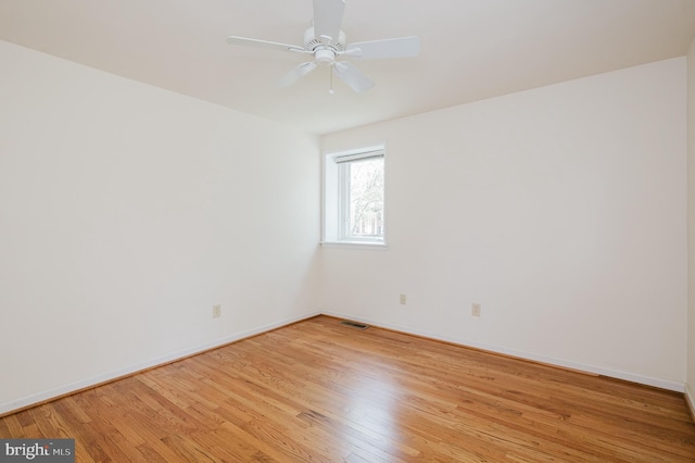 spare room featuring baseboards, light wood finished floors, and visible vents