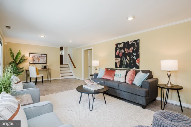 living area featuring crown molding, baseboards, visible vents, and stairway
