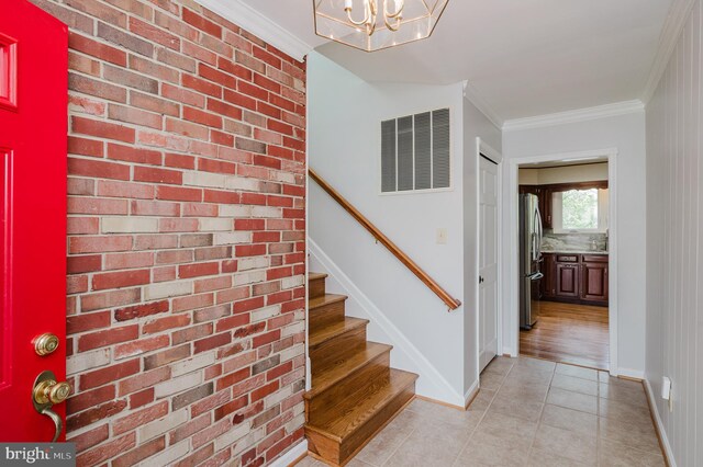 staircase with crown molding, a notable chandelier, tile patterned flooring, baseboards, and visible vents