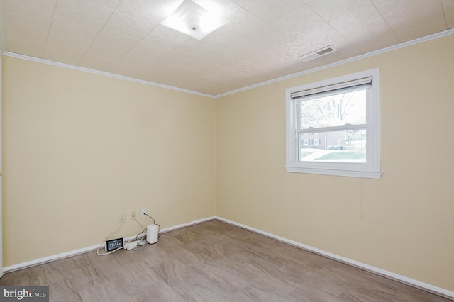 spare room featuring baseboards, ornamental molding, and visible vents