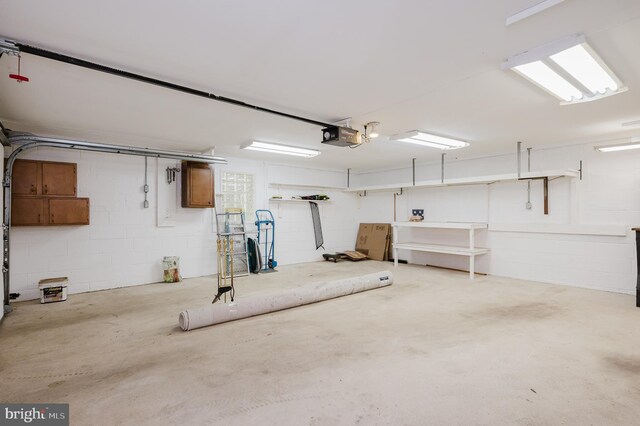 garage with a garage door opener and concrete block wall