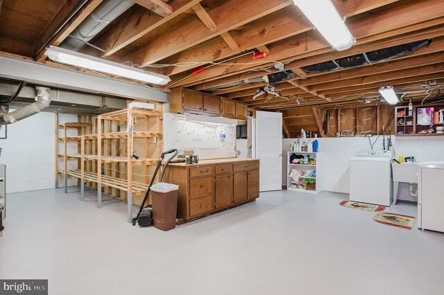 unfinished basement featuring concrete block wall, a workshop area, and washer and clothes dryer