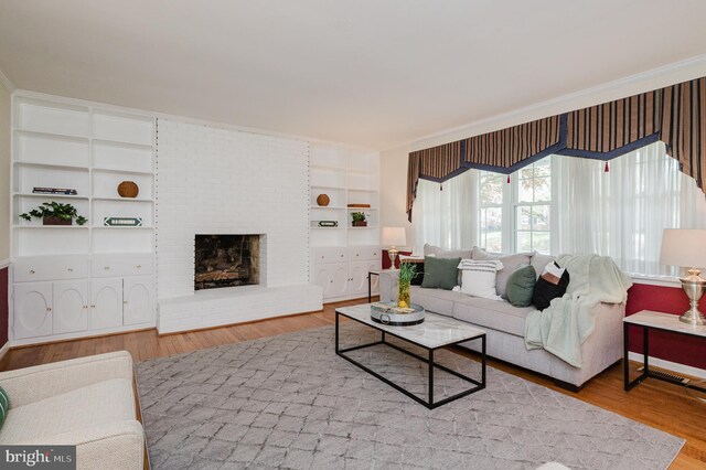 living room with built in shelves, wood finished floors, and a fireplace