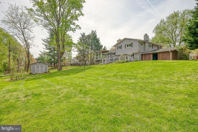 view of yard featuring fence, a storage unit, and an outbuilding