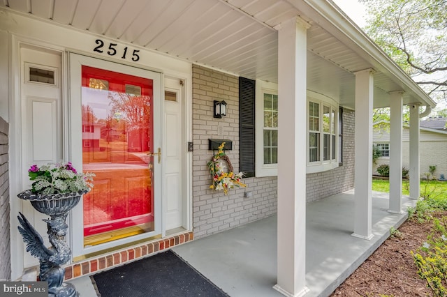 property entrance featuring a porch and brick siding