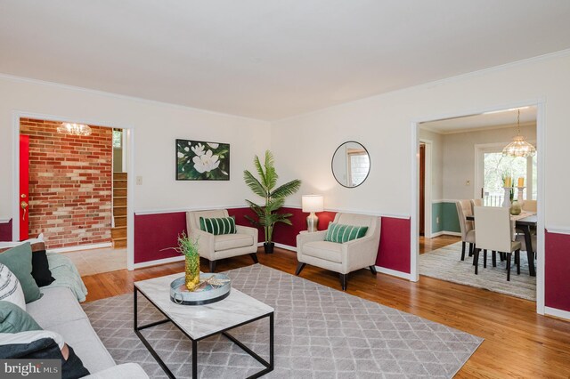 living room with ornamental molding, wood finished floors, and a notable chandelier