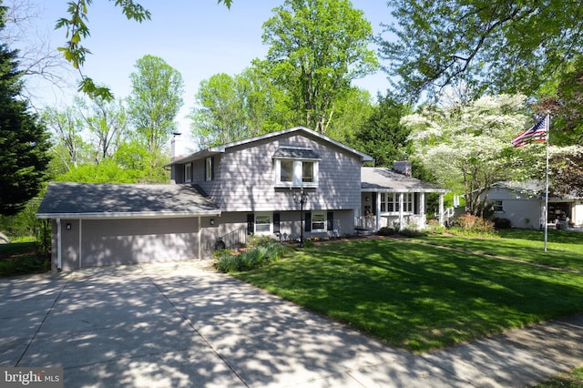 tri-level home with a garage, a front lawn, a chimney, a porch, and driveway