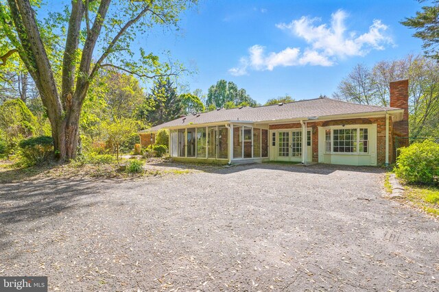 6611 Jupiter Dr, Huntingtown, MD 20639 - rear view of house with french doors, a chimney, a sunroom, brick siding, and driveway
