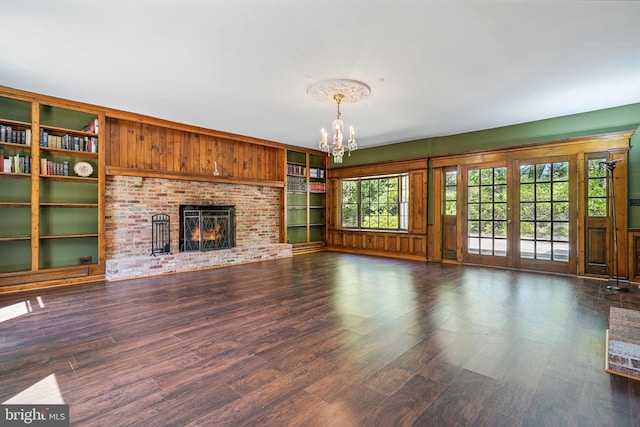 6611 Jupiter Dr, Huntingtown, MD 20639 - unfurnished living room featuring dark wood-type flooring, a brick fireplace, a notable chandelier, and built in shelves