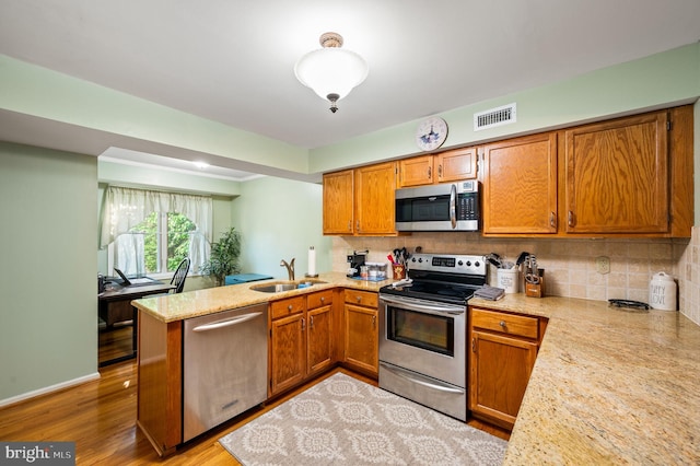 55 E Harrison Rd E Unit 55, West Chester, PA 19380 - kitchen with appliances with stainless steel finishes, a peninsula, brown cabinetry, and decorative backsplash