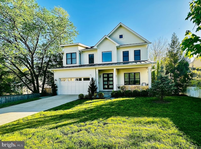 traditional-style home with stucco siding, a standing seam roof, a garage, a front yard, and concrete driveway