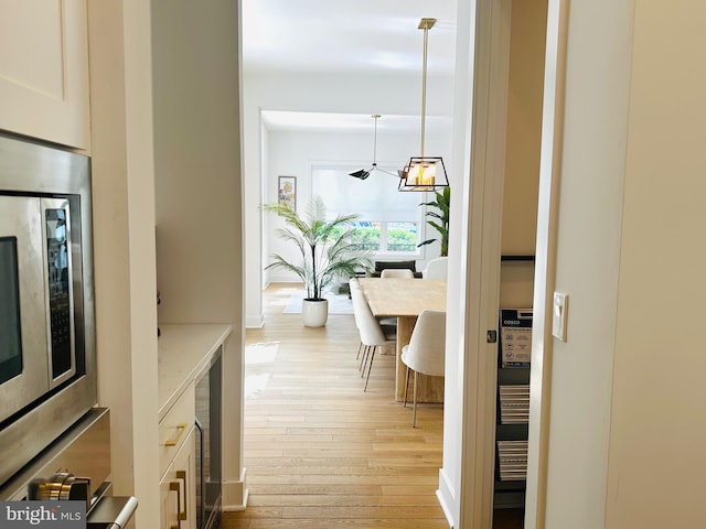 hallway with a notable chandelier and light wood finished floors