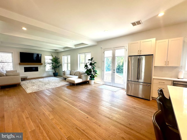living room with recessed lighting, beam ceiling, visible vents, light wood-style flooring, and baseboards