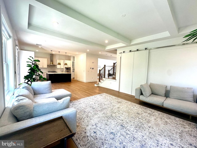 living room with a barn door, light wood-type flooring, stairway, and recessed lighting