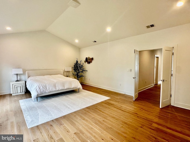 bedroom featuring wood finished floors, visible vents, vaulted ceiling, and baseboards