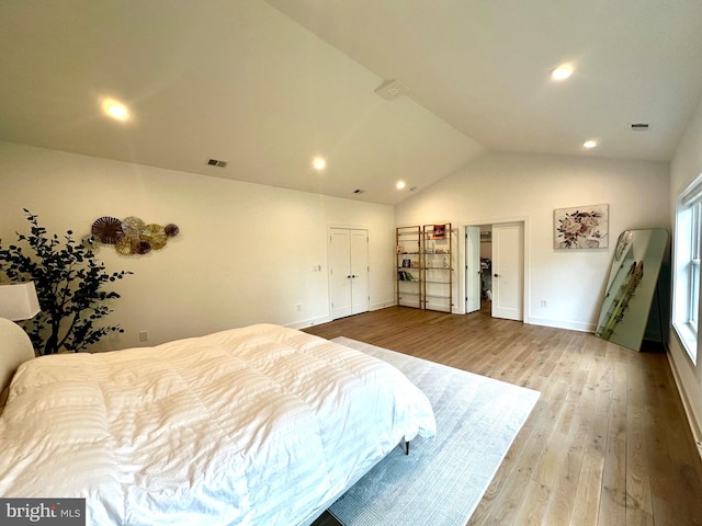 bedroom with baseboards, visible vents, wood finished floors, and vaulted ceiling