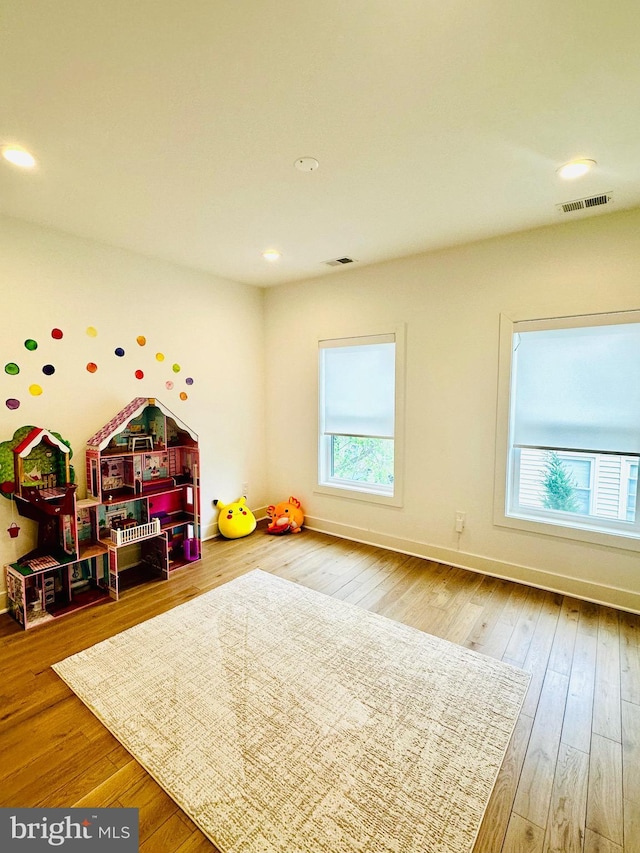 playroom featuring wood-type flooring, visible vents, and a wealth of natural light